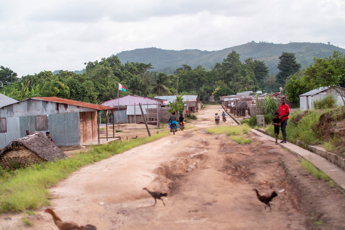 Route traversant un village à Madagascar, avec maisons et collines